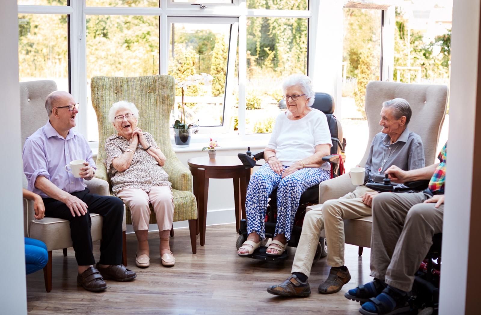 A group of older adults enjoy each other's company in their assisted living community common area.
