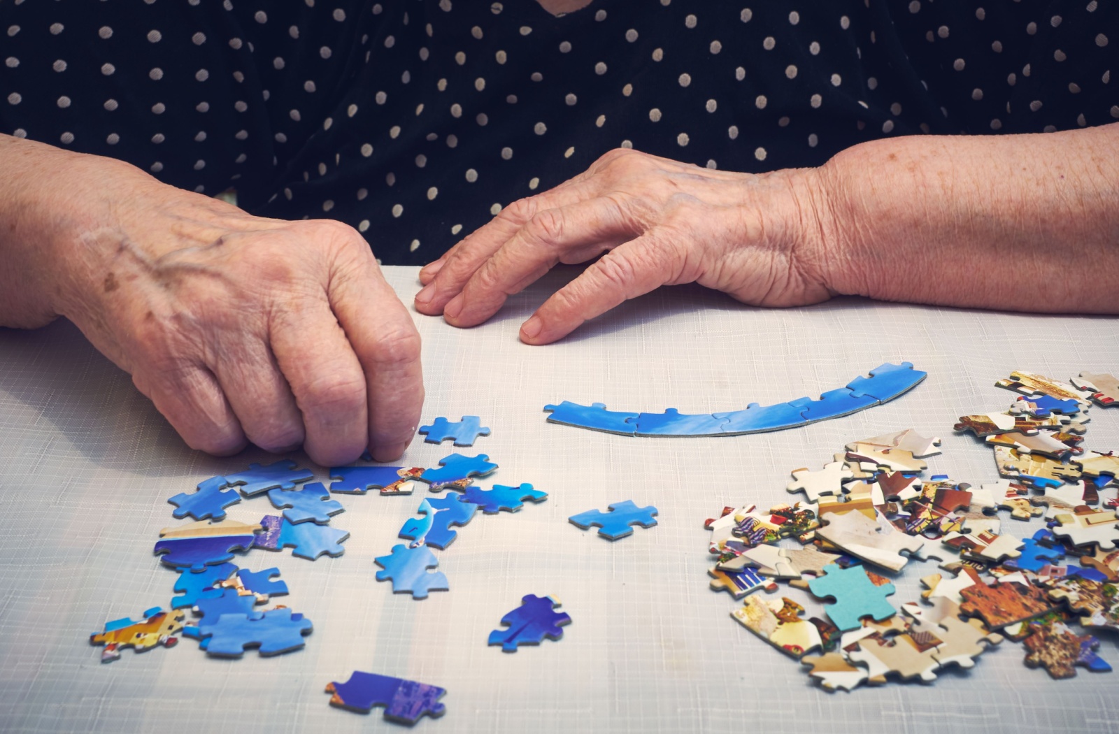 A senior resident starts on a jigsaw puzzle, keeping themselves mentally active.