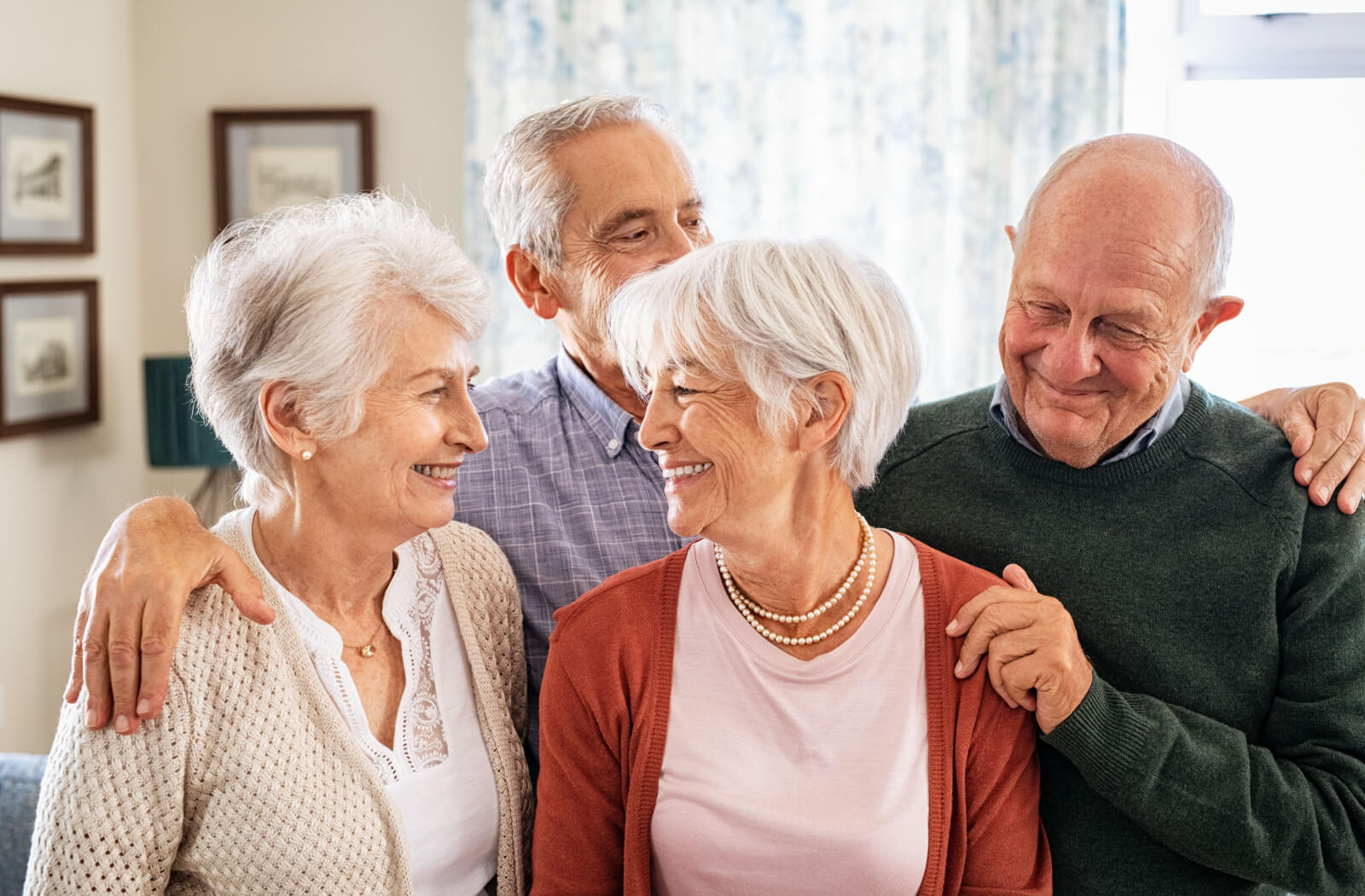 4 older adults standing and smiling at the camera in a senior living community.