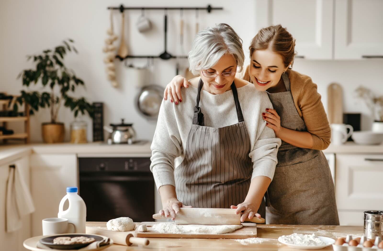 A senior mother and their adult child enjoy baking together.