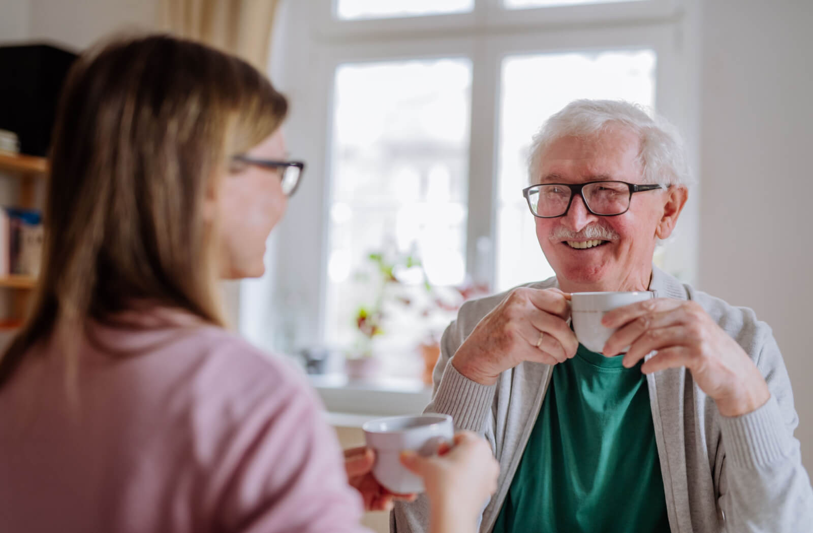 A senior father and his daughter sitting and enjoying a cup of tea together