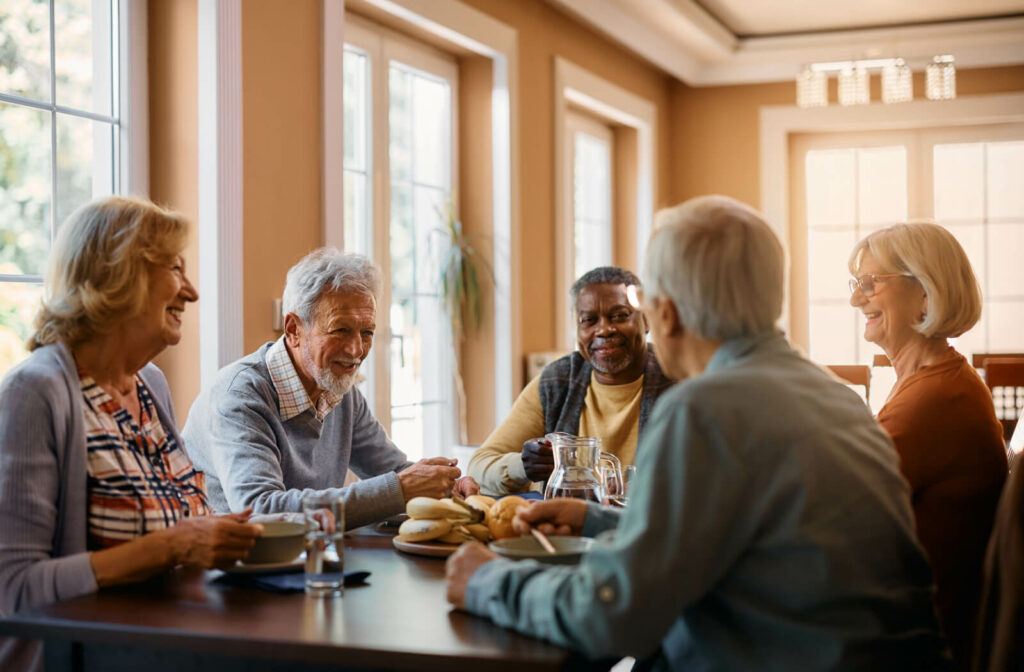 A group of seniors sitting around a table, eating and enjoying breakfast while smiling and chatting with each other